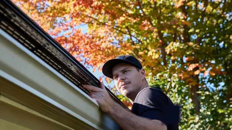 Installer inspecting an Alu-Rex gutter guard under Colorado autumn sun