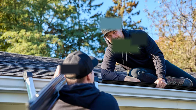 Team fitting Alu-Rex gutter protection along a brick home near Durango
